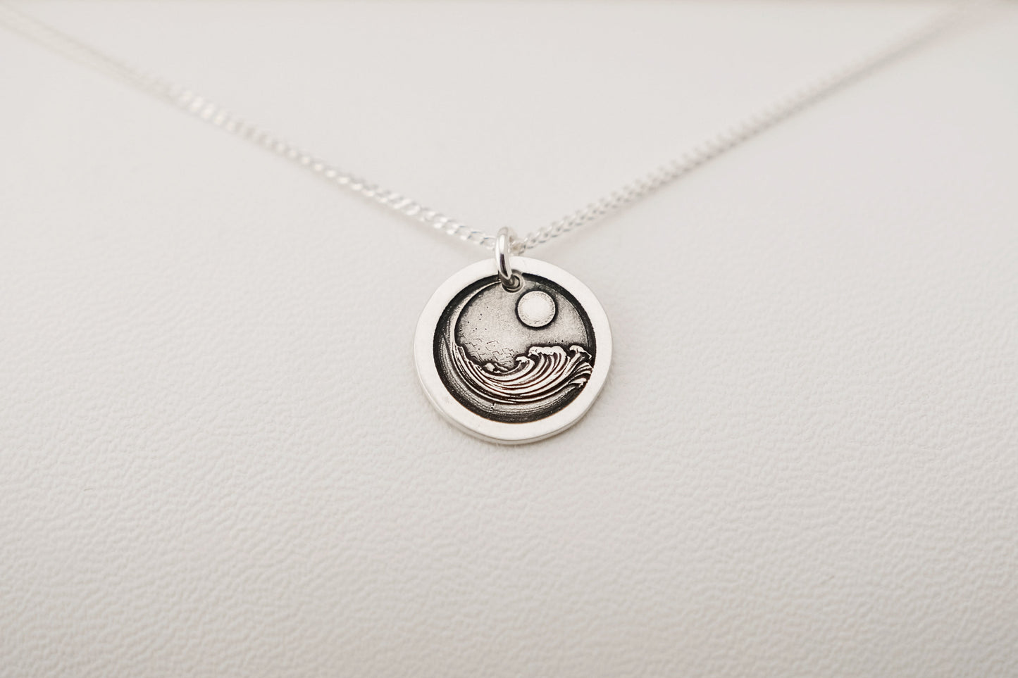 Silver necklace with a circular pendant on a light gray background
