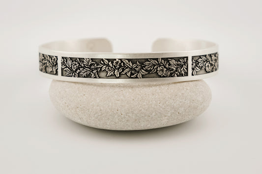 Silver bracelet with floral pattern on a white background