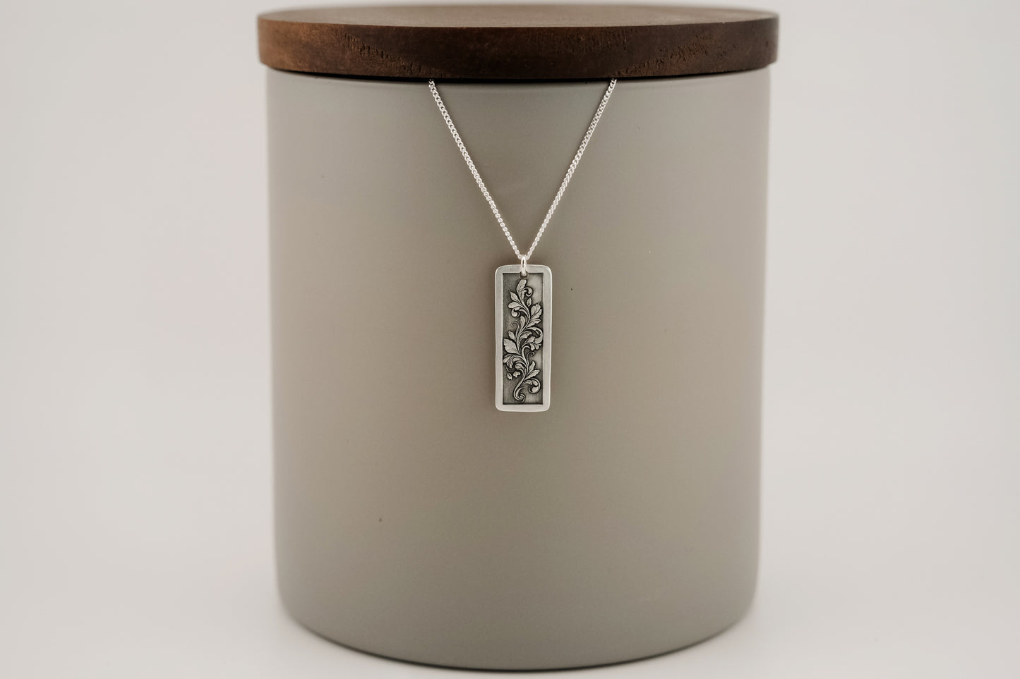 Silver pendant with an engraved floral design on a neutral background