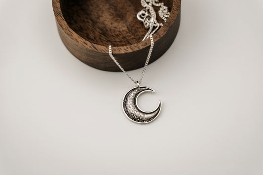 Silver moon-shaped necklace on a white background