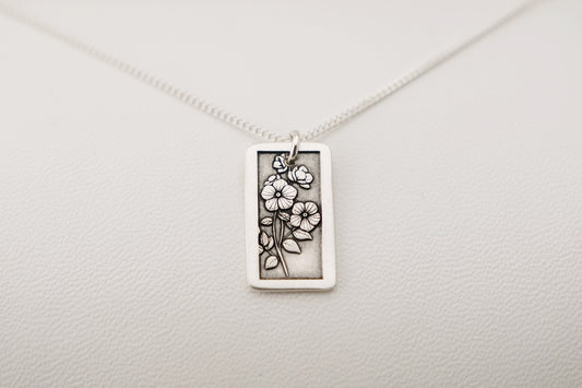 Silver necklace with a rectangular pendant on a light gray background