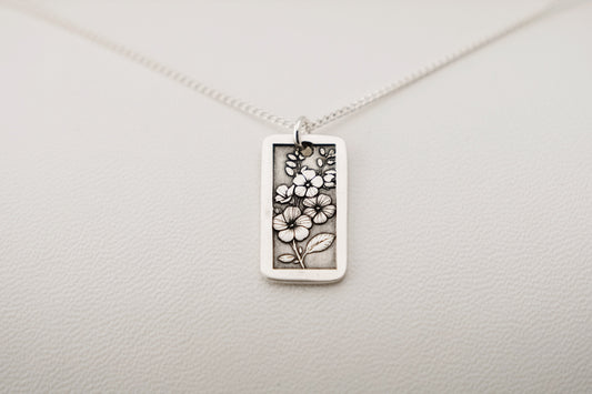 Silver necklace with a floral pendant on a light gray background