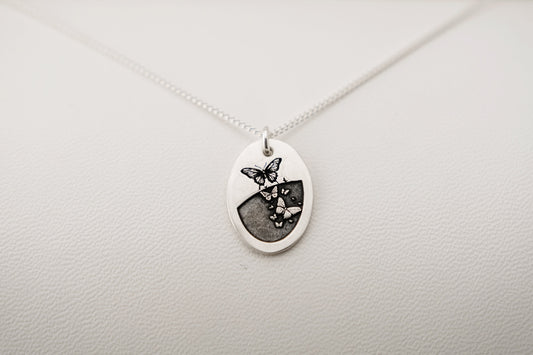 Necklace with a pendant featuring a butterfly design on a light gray background