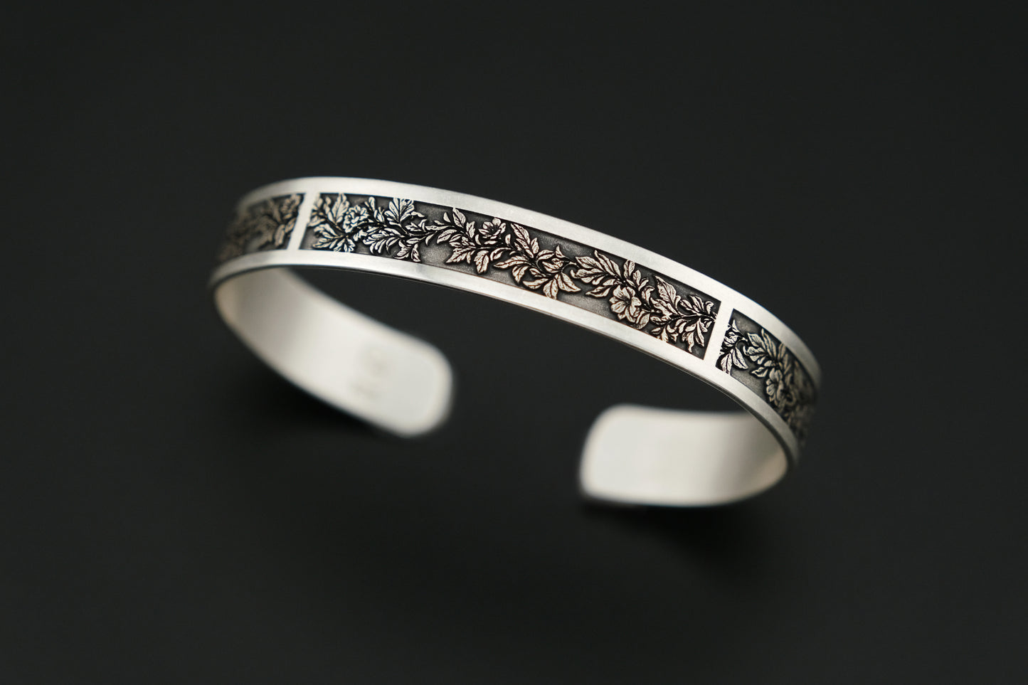 Silver bracelet with intricate design on a black background