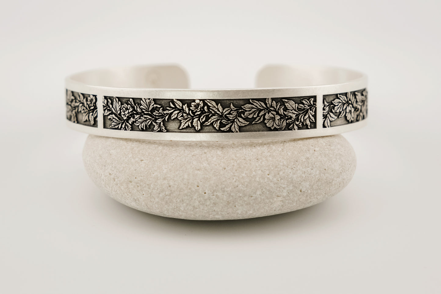 Silver bracelet with floral pattern on a white background