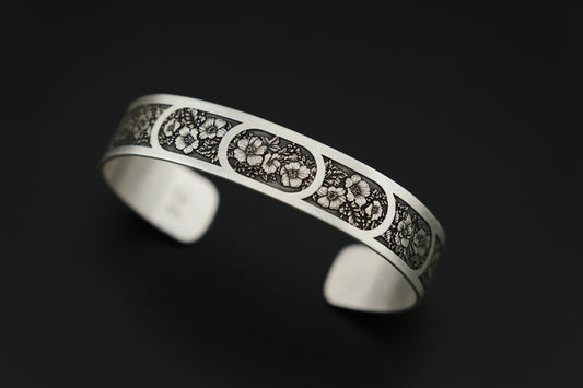Silver bracelet with intricate designs on a black background