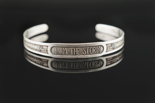 Silver bracelet with 'I AM THE STORM' engraving on a black background