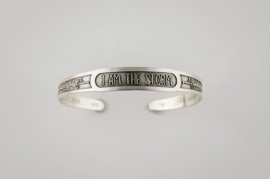 Silver bracelet with 'I AM THE STORM' engraving on a light gray background